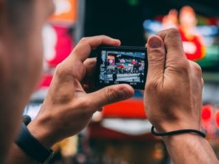 Un chinois prenant une photo avec son smartphone.