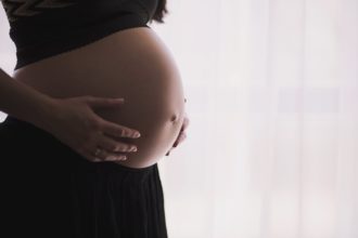 Une femme enceinte caressant son ventre arrondi (Photo : Unsplash).