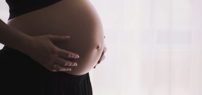 Une femme enceinte caressant son ventre arrondi (Photo : Unsplash).