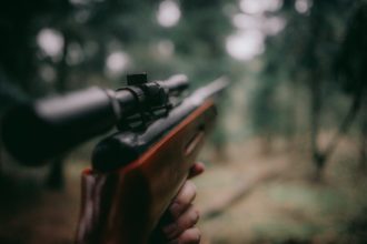 Un chasseur regardant dans le viseur de son fusil.